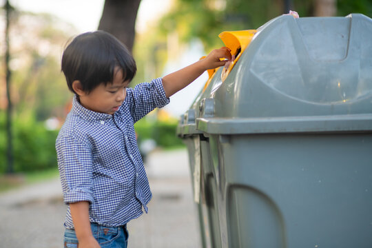 Adorable little boy keep garbage clean to bin in park