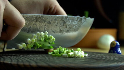 Cutting fresh green onions on a cutting board.
Cutting fresh green onions on a wooden cutting board