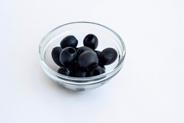 Black olives in a glass bowl isolated on a white background