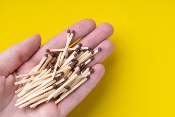 Heap of wooden matchstick in a female palm on a yellow background