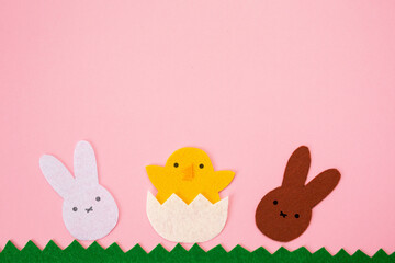 Obraz na płótnie Canvas Happy Easter concept. Cut out the felt applications of white and brown rabbits and the chicken hatched from the egg. Pink background. Flat lay. Copy space