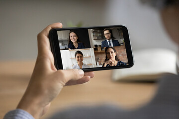 Fototapeta na wymiar Close up of woman hold modern smartphone gadget have webcam digital online meeting with diverse businesspeople. Female employee talk speak on video call on cellphone with smiling colleagues.