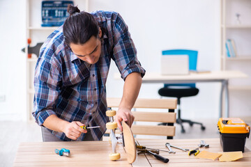 Young man repairing skateboard at workshop