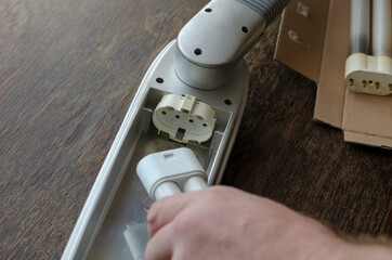 Adult Man's hand installs a new compact fluorescent lamp in the light fixture.