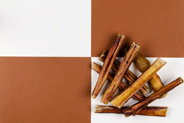 Dried bovine penis, bully sticks, beef pizzle for dogs on a brown and white background.