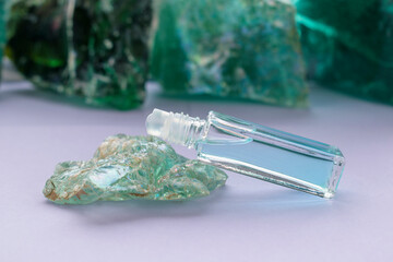Glass bottle with ball dispenser. A tilt on the glass of an abstract form in green with mother-of-pearl highlights. Liquid color - Polo Blue. The concept of perfume, aromatic essential oils.