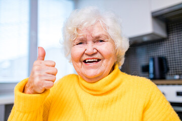 Senior woman showing thumbs up in in living room