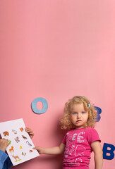 Portrait of  little girl of 2-3 years on speech therapy.Concept over pink  background
