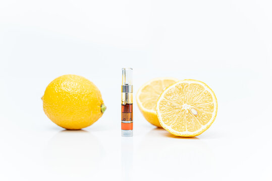 Cannabis vape cartridge and lemons on a white background. Limonene terpene concept.