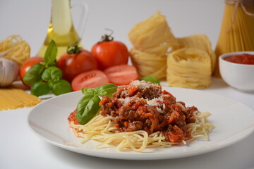 Traditional Italian spaghetti Bolognese  served on a white plate with tomatoes and basil