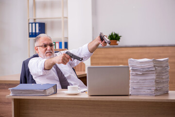 Old male employee holding gun unhappy with excessive work