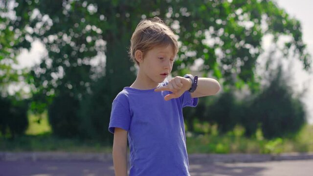 A little boy on a street talks to his parent using his smartwatches. Children security concept
