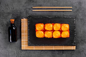 Baked roll with shrimp and masago caviar cap. Traditional sushi restaurant dish, menu item. National japanese cuisine appetizer. Delicious oriental snack, gourmet seafood on wooden platter closeup