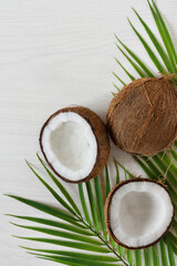Fototapeta na wymiar Coconuts with palm leaf on white wooden background.