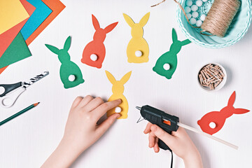 DIY Easter home decor from natural materials. Hands make garland of colored paper, twine and...
