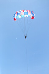 men are gliding using a parachute on the background of the blue sky.