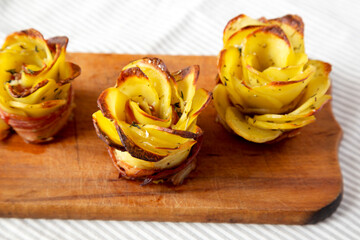 Homemade Potato Roses on a rustic wooden board, side view.
