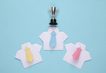Origami shirts with ties and winner cup.on blue background. Leadership, rivalry, business concept