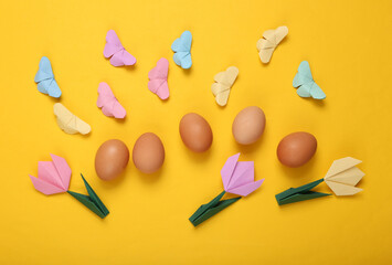 Easter composition of origami tulips and butterflies, eggs on a yellow background