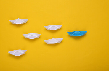 Leadership concept. Origami paper boats on yellow background