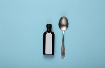 Cough syrup bottle and spoon on blue background