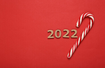 Fototapeta na wymiar 2022 and striped candy cane on red background. Christmas, new year composition