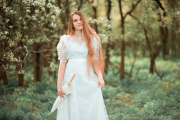 Obraz na płótnie Canvas A girl in a park in a white dress and with an umbrella