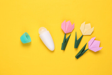 Antiperspirant stick and origami tulips on yellow background