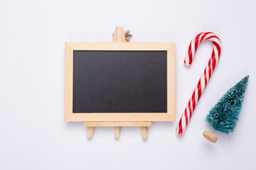 Mini blackboard with Christmas tree, candy on white background. Chalkboard with copy space. New year, Christmas still life