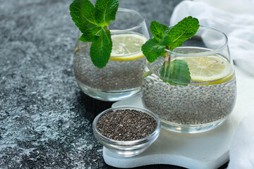 Two glasses of water with chia seeds and lemon on a black background.Copy space.
