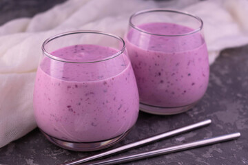 Two glasses of blueberry smoothies on a gray background.
Close-up.