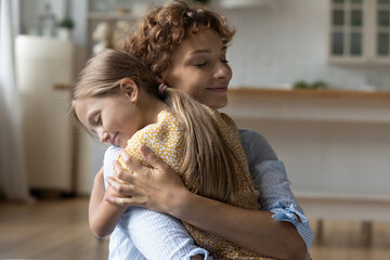 Not a stepmother but foster mommy. Affectionate young woman custodian hold in tight embraces caress happy little girl stepchild at adoption day. Tender mom cuddle strain to bosom small daughter kid