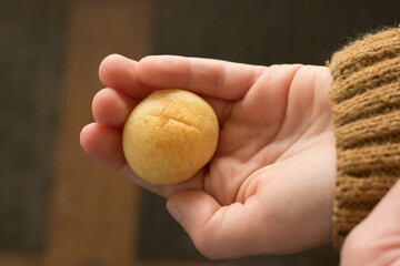 Hands holding pan de queijo, a Brazilian mini cheese bread finger food, party food and snack