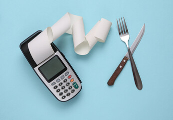 Payment terminal with a fork and knife on a blue background. Payment at the restaurant