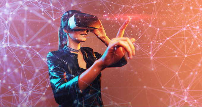 Young girl getting experience VR headset is using augmented reality eyeglasses being in virtual reality. Girl with hands up wearing virtual reality goggles. Woman touching air during VR experience - Powered by Adobe