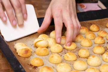 Hands holding pan de queijo, a Brazilian mini cheese bread finger food, party food and snack