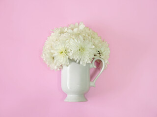 Coffee or tea cup with white flower inside on a pink background. minimal flat lay