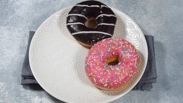 Donuts in the glaze on the plate. The man takes a doughnut and puts it on a plate.