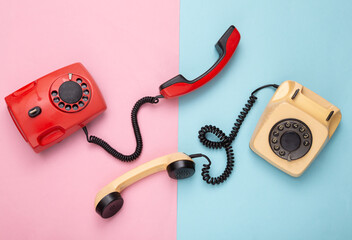 Retro red old fashioned rotary phones on pink blue background. Top view