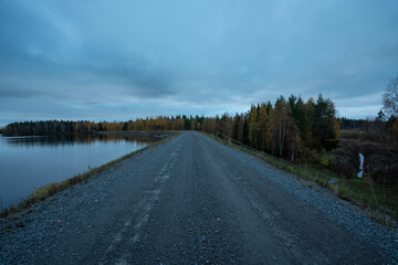 Man made lake with dike as road with boreal forest and low vegitation in autumn