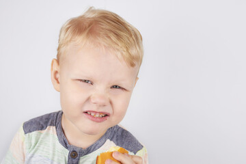 Three-year-old boy eats a pie on a white background.