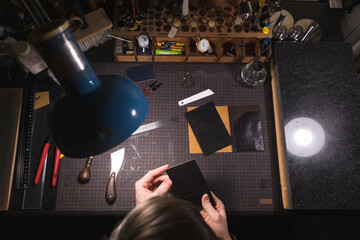 Top view - male tanner working on workplace with leather. Handmade in a small manufactory. The...