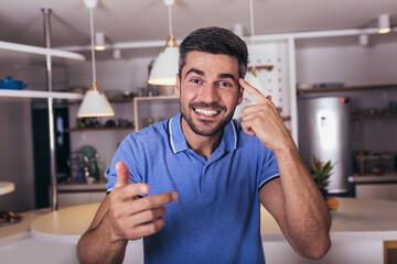 Image of a positive smiling young man indoors at home looking camera.