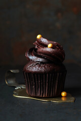 Schokoladencupcake mit Schokoladenfrosting und goldenen Zuckerperlen