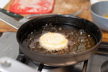 Frying chicken nuggets in oil on a frying pan