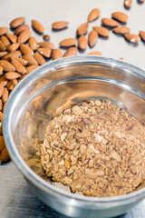 Lots of almonds and powdered almonds sprinkled on gray metal background
