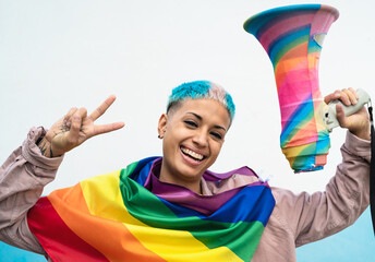 Young woman celebrating gay pride event wearing rainbow flag symbol of Lgbt social movement