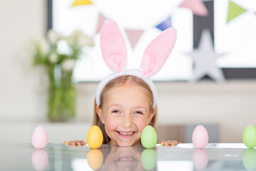 Pretty little girl wearing bunny ears and holding basket with easter eggs at home during coronavirus covid-19 outbreak. 