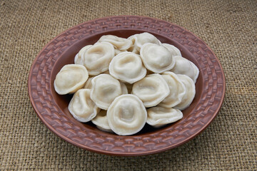Dumplings in a brown plate on burlap