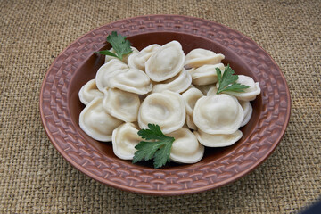 Dumplings in a brown plate on burlap